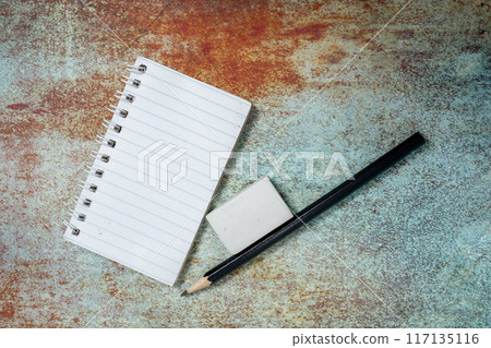 Blank notepad, eraser and black pencil on a table Blank notepad, eraser and black pencil on a table 117135116