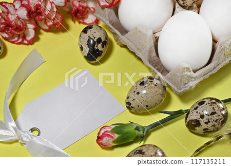 Easter eggs on rustic table with cherry blossoms. Happy Easter. Natural dyed colorful eggs in paper tray with linen napkin and spring flowers in rustic room. Countryside still life 117135211