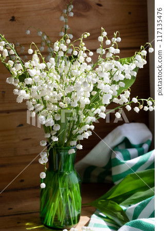 Bouquet white flowers Lily of the valley in glass ( Convallaria majalis, May bells, may-lily ) on a white table with space for text Bouquet white flowers Lily of the valley in glass ( Convallaria majalis, May bells, may-lily ) on a white table with space for text 117135476