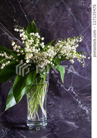 Bouquet white flowers Lily of the valley in glass ( Convallaria majalis, May bells, may-lily ) on a white table with space for text Bouquet white flowers Lily of the valley in glass ( Convallaria majalis, May bells, may-lily ) on a white table with space for text 117135478