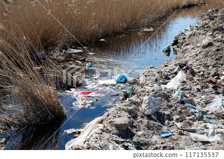 Trash pile near water is pollution harming natural landscape Trash pile near water is pollution harming natural landscape 117135537