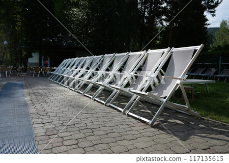 Row of sunloungers near the swimming pool, lounge chairs 117135615