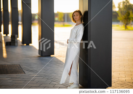Young woman in formal clothes walking near grey wall outdoors, space for text 117136095