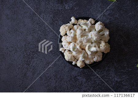 Raw cauliflower, black pepper peas and a wooden spoon with coarse salt lie on a gray background. Selective focus. Vegetable layout. Copy space. The view from the top. 117136617