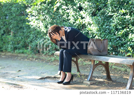 Woman holding her head in the park 117136819