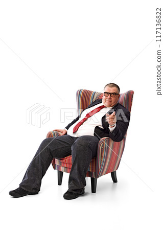 Businessman in black suit and red tie, in glasses sitting with serious face in armchair, having meeting pointing with finger isolated on white background. Giving advice Businessman in black suit and red tie, in glasses sitting with serious face in armchair, having meeting pointing with finger isolated on white background. Giving advice 117136822