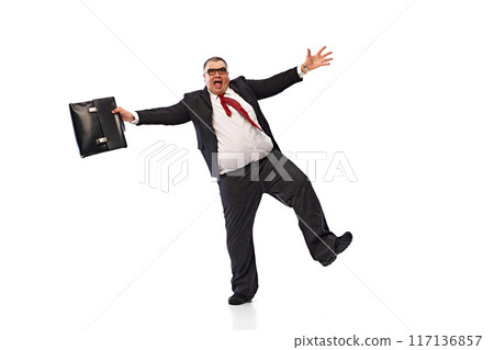 Happy and excited fat man, businessman in black suit, formal wear dancing emotionally with briefcase isolated on white background. Progress. Happy and excited fat man, businessman in black suit, formal wear dancing emotionally with briefcase isolated on white background. Progress. 117136857