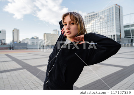 Young Woman Posing Gracefully Outside Modern City Buildings During Late Afternoon Young Woman Posing Gracefully Outside Modern City Buildings During Late Afternoon 117137529