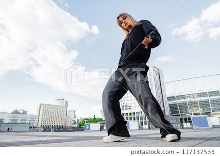 Urban Dance Performer Showcases Fluid Movement Against City Skyline During Daylight Hours 117137533
