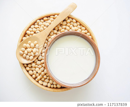 Soy milk in a spoon with soybeans on bowl isolated white background, top view 117137839