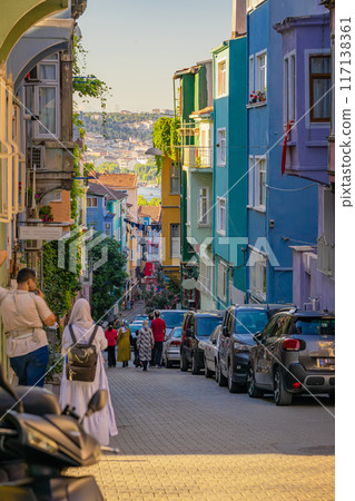 Colorful urban street with people walking, parked cars, vibrant buildings, lively atmosphere in charming neighborhood Colorful urban street with people walking, parked cars, vibrant buildings, lively atmosphere in charming neighborhood 117138361