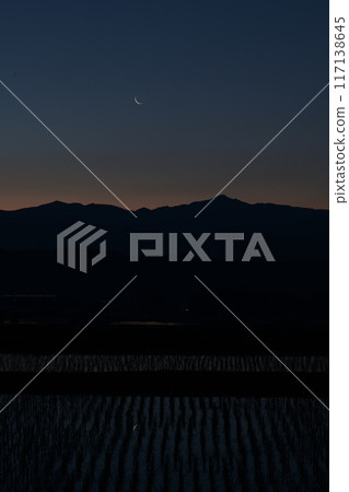 A thin, light-colored moon with a lunar age of 28.0 is reflected between the rice seedlings above the Okuchichibu mountain range, as seen from Hakushu Town, Hokuto City. A thin, light-colored moon with a lunar age of 28.0 is reflected between the rice seedlings above the Okuchichibu mountain range, as seen from Hakushu Town, Hokuto City. 117138645