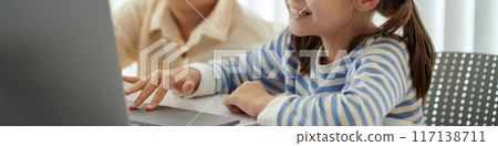 Smiling Young Girl Using Laptop at Classroom Table 117138711