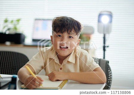 Smiling Child Writing in Modern Home Office Setting Smiling Child Writing in Modern Home Office Setting 117138806