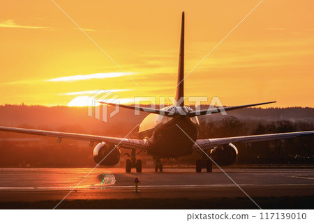Airplane taxiing to airport runway at sunset . 117139010