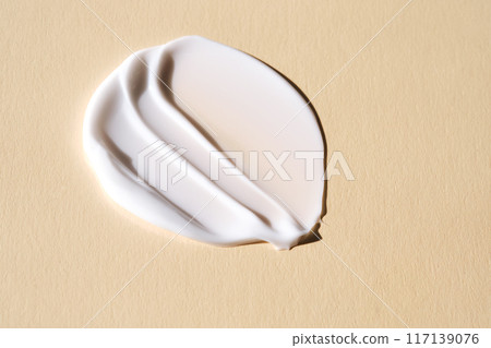 A smear of white cream on a beige background. 117139076
