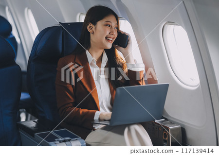 .Young Asian executive excels in first class, multitasking with digital tablet, laptop and smartphone. Travel in style, work with grace. .Young Asian executive excels in first class, multitasking with digital tablet, laptop and smartphone. Travel in style, work with grace. 117139414