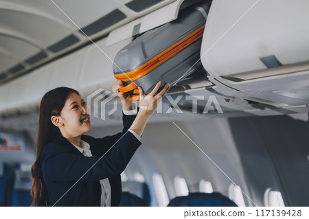 Female tourist packing her luggage in the airplane cabin. Female tourist packing her luggage in the airplane cabin. 117139428