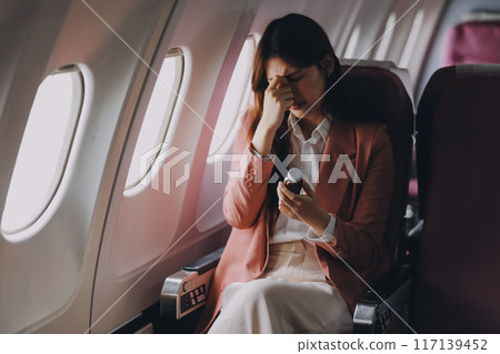 Tired asian woman with headache feeling sick while sitting in the airplane , Passengers near the window. 117139452
