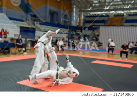 Blurred defocused image with two karate practitioners sparring on a tatami mat. 117140800