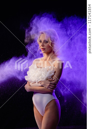 Woman posing with purple particles sprayed in air Woman posing with purple particles sprayed in air 117141854