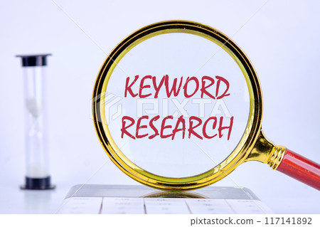 KEYWORD RESEARCH written through a magnifying glass on a uniform light background KEYWORD RESEARCH written through a magnifying glass on a uniform light background 117141892