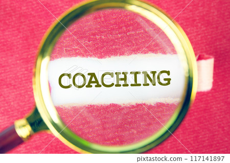 Coaching and Mentoring Concept. COACHING written through a magnifying glass under a torn paper Coaching and Mentoring Concept. COACHING written through a magnifying glass under a torn paper 117141897