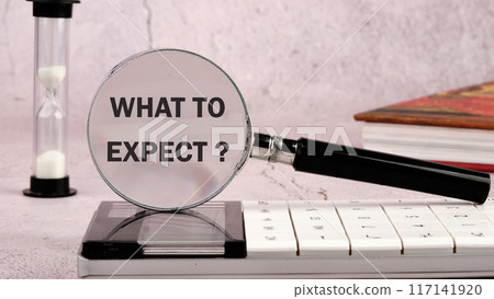 Business concept. What Do You Expect question through a magnifying glass on a gray wall, front view Business concept. What Do You Expect question through a magnifying glass on a gray wall, front view 117141920