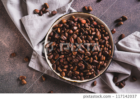 Close up of ripe pine nuts in the shells on a plate on the table top view Close up of ripe pine nuts in the shells on a plate on the table top view 117142037