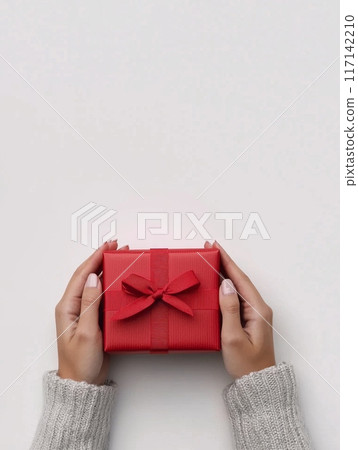 Woman holding red gift box with ribbon on white background 117142210