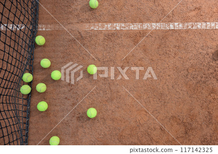 A yellow tennis balls lies on the clay court. 117142325