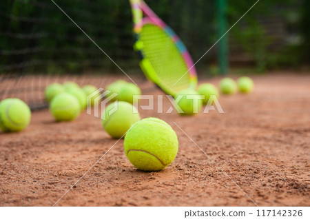 A yellow tennis balls lies on the clay court. 117142326
