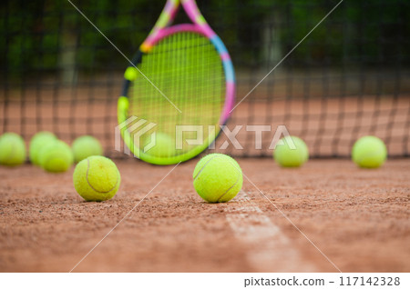 A yellow tennis balls lies on the clay court. A yellow tennis balls lies on the clay court. 117142328
