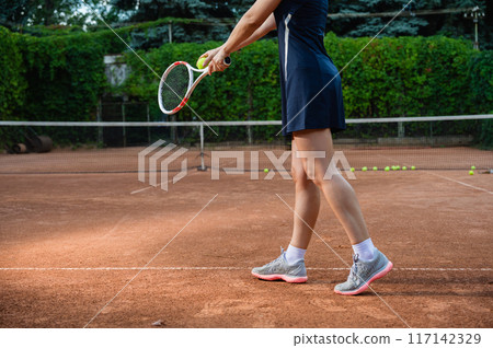 Unrecognizable female tennis player serving. 117142329
