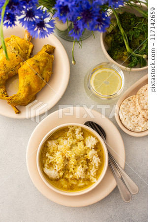 Stewed rabbit with rice, broccoli and rice cakes, a served table with food and a vase of flowers Stewed rabbit with rice, broccoli and rice cakes, a served table with food and a vase of flowers 117142659