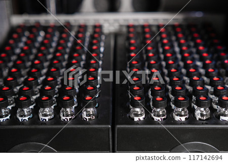 HPLC glass vials with black caps are positioned in the autosampler, awaiting injection HPLC glass vials with black caps are positioned in the autosampler, awaiting injection 117142694