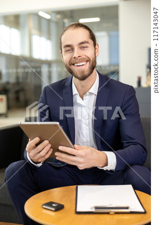 Handsome man working on digital tablet in car showroom 117143047