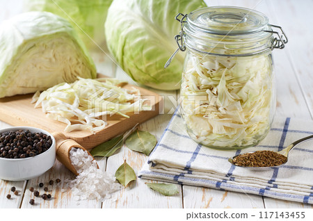 Pickling cabbage at home on table. Prepare homemade sauerkraut or fermented cabbage. Pickling cabbage at home on table. Prepare homemade sauerkraut or fermented cabbage. 117143455