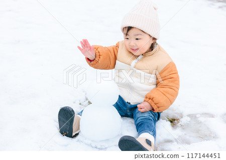 Infant (1 year old) making and playing with a snowman 117144451