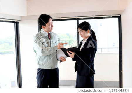 Image of a male employee in work clothes getting angry at a young female office worker in a suit 117144884