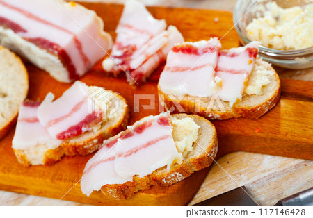 Traditional Russian and Ukrainian food, salted smoked pork bacon with horseradish on wooden background 117146428