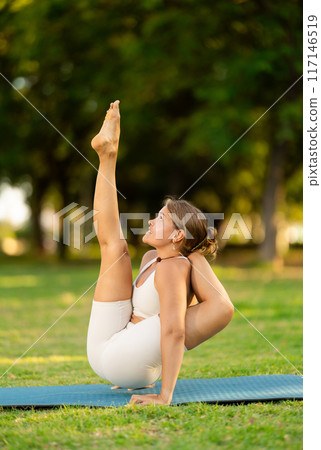 Sporty girl doing arm balancing Elephant Trunk Pose in summer park 117146519