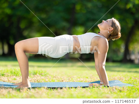 Girl performing Reverse Table Top Pose in summer park 117146537