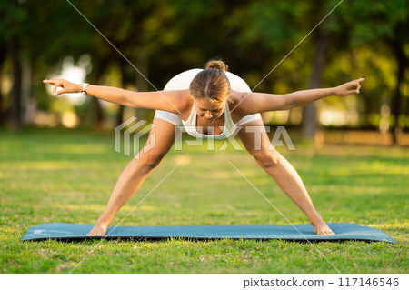 Girl in park on green grass of lawn performs Himavanasana Girl in park on green grass of lawn performs Himavanasana 117146546