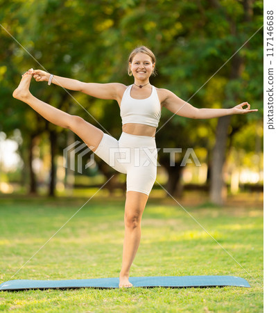 Girl in park on green grass of lawn performs Utthita Hasta Padangushthasana Girl in park on green grass of lawn performs Utthita Hasta Padangushthasana 117146688