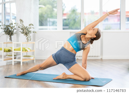 Lover of active lifestyle on yoga mat perform doing elongated side angle in gym 117146783
