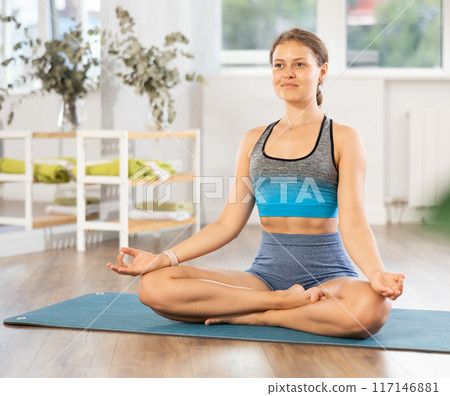 Relaxed girl meditating in lotus position with hands in mudra 117146881