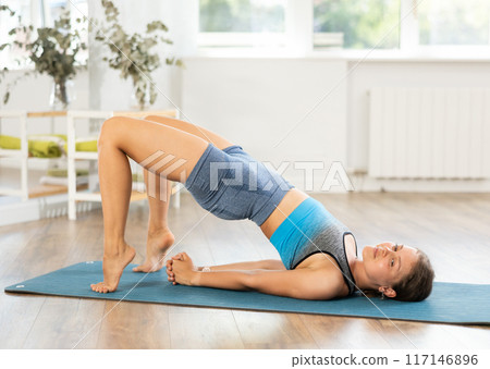 Young girl performing shoulder supported bridge in yoga studio Young girl performing shoulder supported bridge in yoga studio 117146896