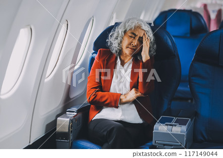 Mature with headache with nausea feeling sick while sitting in the airplane , Passengers near the window. Mature with headache with nausea feeling sick while sitting in the airplane , Passengers near the window. 117149044