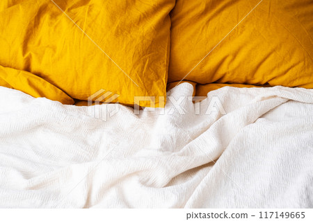 Cozy bed with yellow pillows and white blanket in modern bedroom. Cozy bed with yellow pillows and white blanket in modern bedroom. 117149665